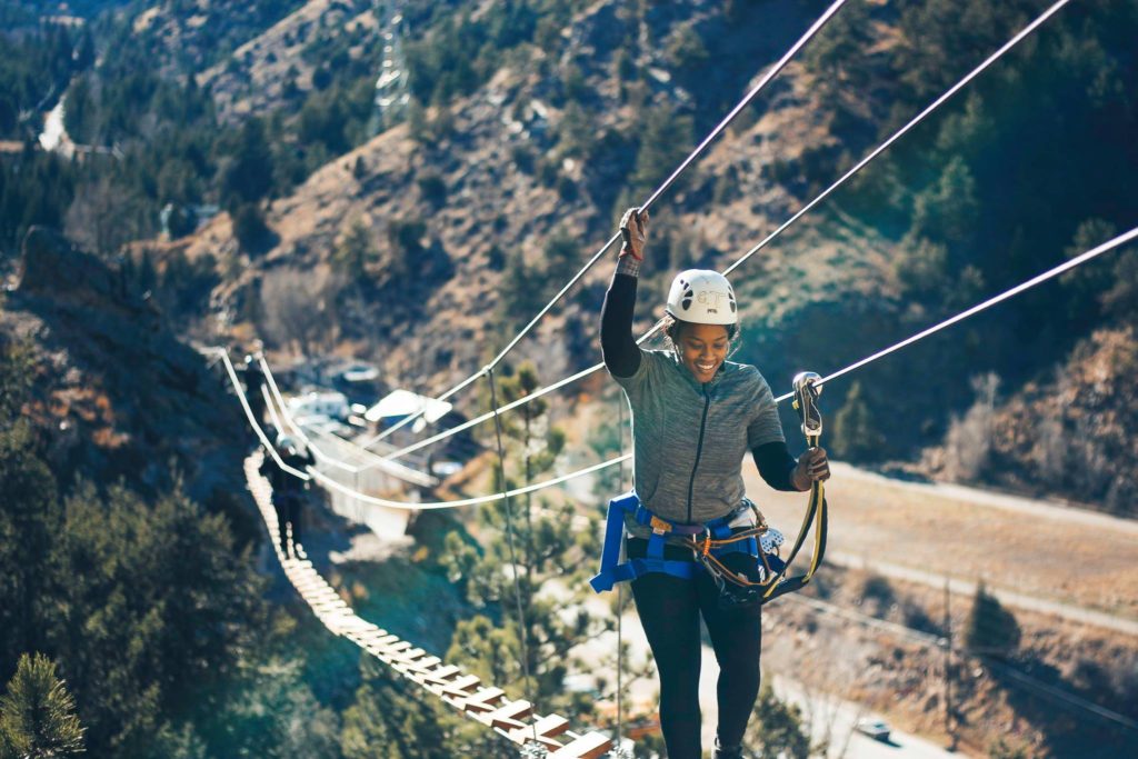 A woman crossing a bridge with a harness and helmet on